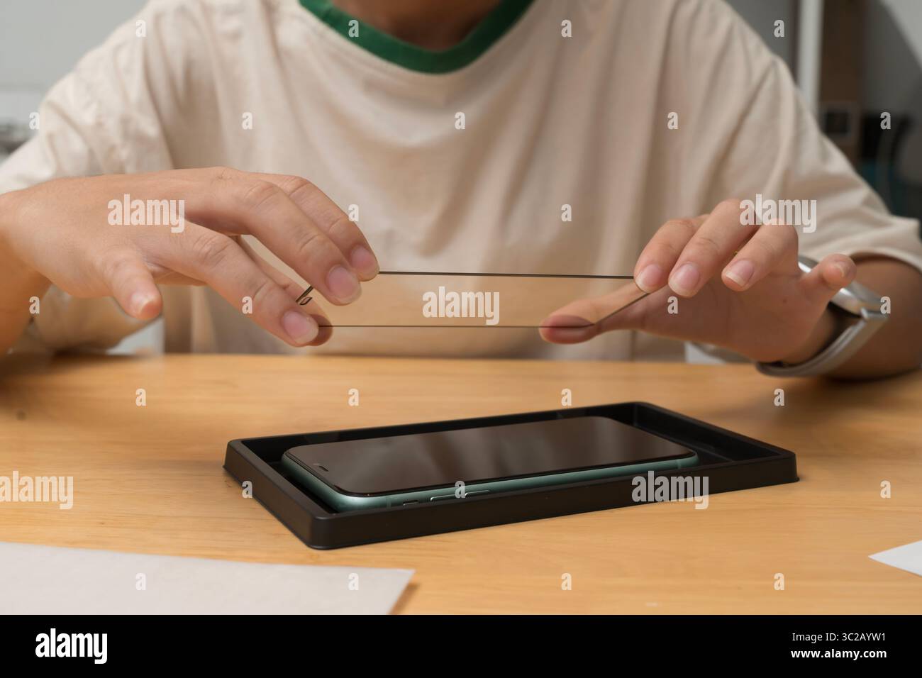 Nahaufnahme einer Person, die den Schutzschirm aus gehärtetem Glas am Smartphone installiert. Letzter Schritt der Anwendung zum Schutz des Geräteschilds vor Kratzern, Staub, Stockfoto