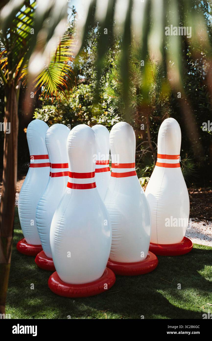 Aufblasbare Bowlingnadeln auf Gras in sonniger Umgebung. Umgeben von üppigem Grün ist dieses verspielte Setup perfekt für Outdoor-Aktivitäten Stockfoto