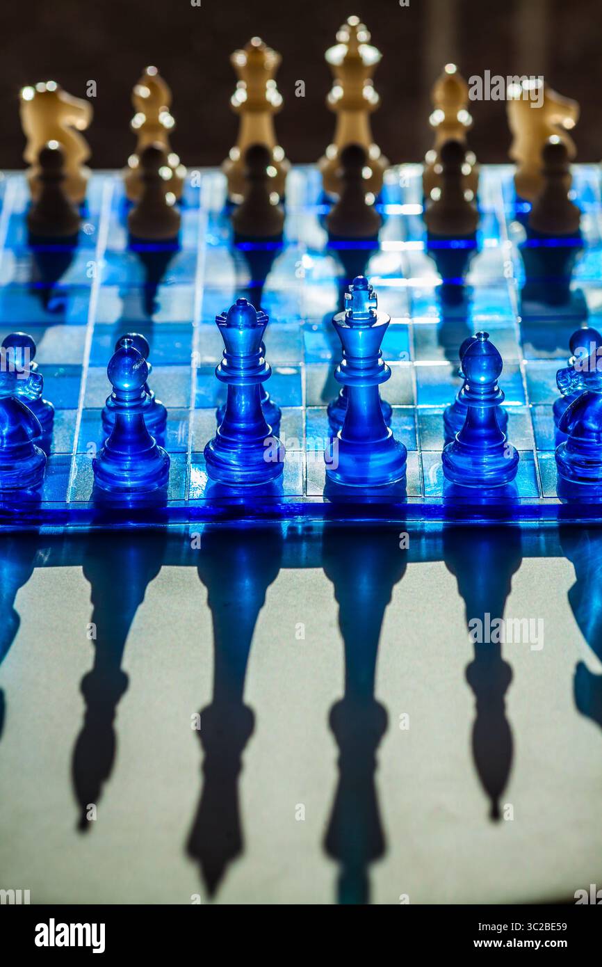 Ein fesselndes Schachbrett mit durchscheinenden blauen Teilen und Quadraten wirft dramatische Schatten und schafft eine visuell eindrucksvolle und strategische Szene Stockfoto