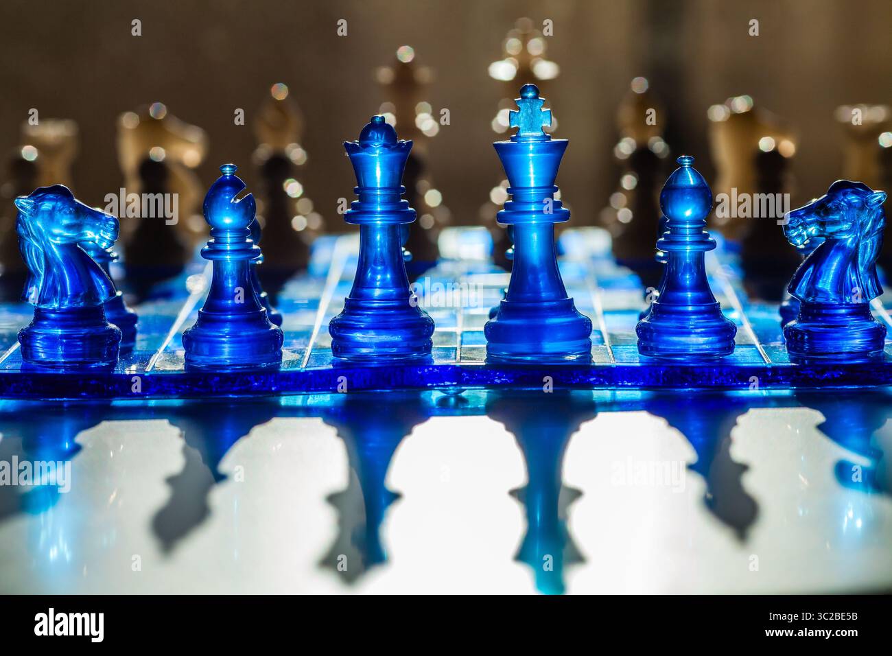 Ein fesselndes Schachbrett mit durchscheinenden blauen Teilen und Quadraten wirft dramatische Schatten und schafft eine visuell eindrucksvolle und strategische Szene Stockfoto