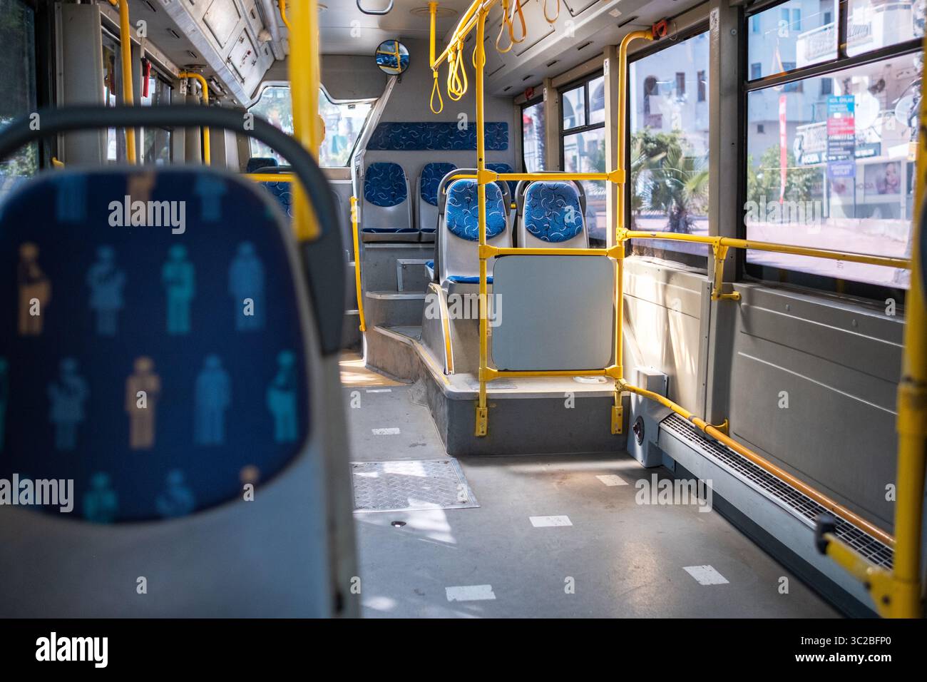 Der Sitzbereich eines öffentlichen Verkehrsbusses ist mit dekorativen Mustern und viel Platz ausgestattet und bietet eine saubere und organisierte Umgebung bei Tageslicht Stockfoto