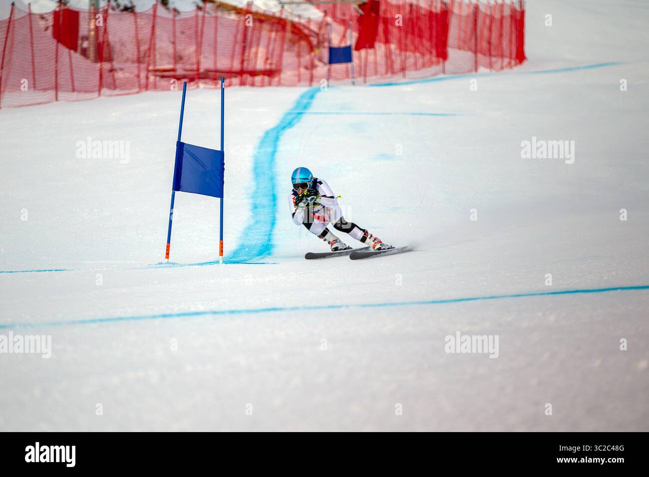 alpines Skirennen bergab auf verschneiten Skipisten vorbei am blauen Tor Stockfoto