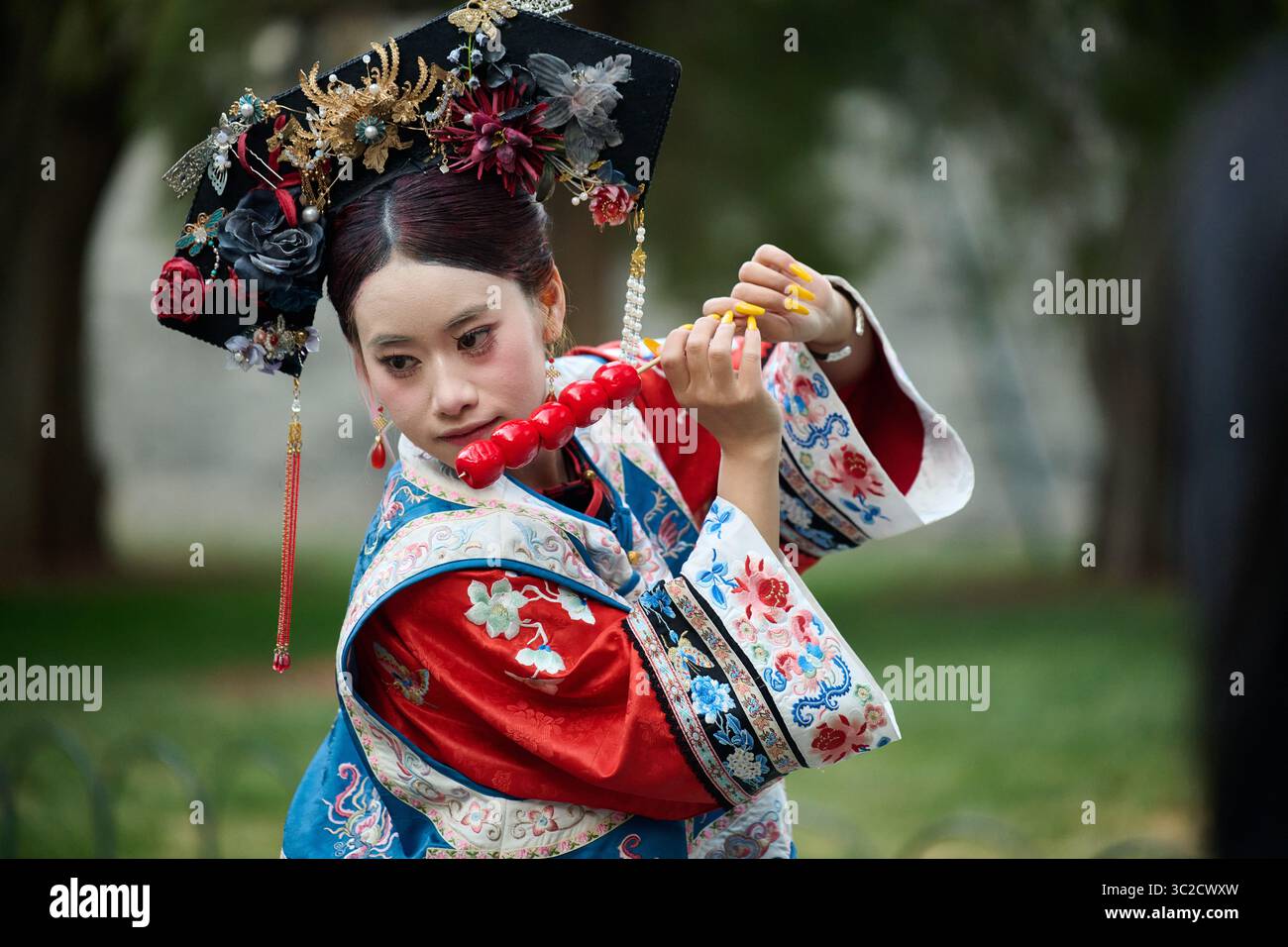 Frau in rot-blauem chinesischen Kostüm tanzt in einer natürlichen Umgebung im Freien Stockfoto