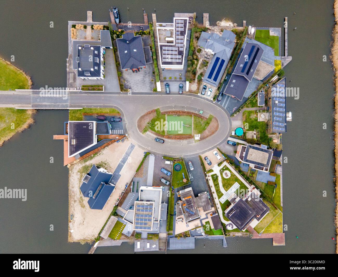 Blick aus der Luft auf moderne Häuser mit Solarpaneelen auf einer künstlichen Insel, umgeben von dunklem Wasser, verbunden durch eine Brücke, Amsterdam, Nord-Holland, Niederlande. Stockfoto
