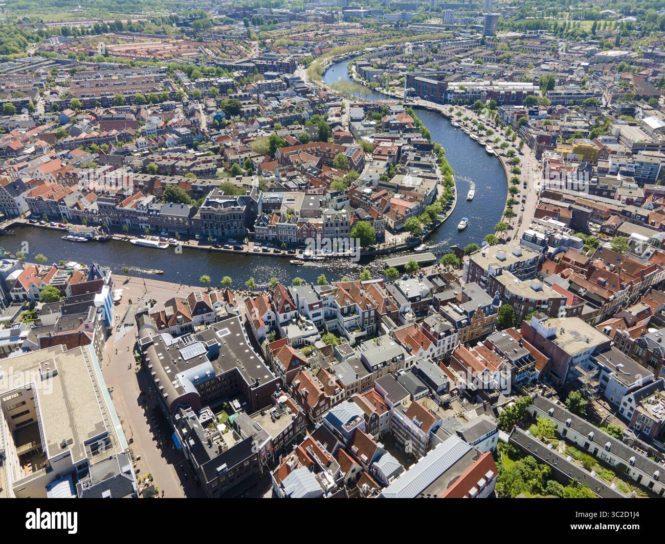Aus der Vogelperspektive auf den sich windenden Fluss, der durch das Herz der Stadt fließt und den Himmel reflektiert, mit Gebäuden entlang der Ufer, Amsterdam, Nordholland, Niederlande. Stockfoto