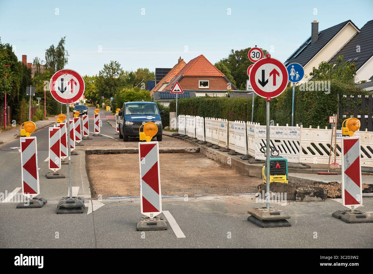 16. Juli 2025 – Sievershagen-Deutschland: Baustelle mit Arbeiterwagen, Sicherheitsbarrieren und Schildern in einem Wohngebiet mit Sonnenkollektordächern. Stockfoto