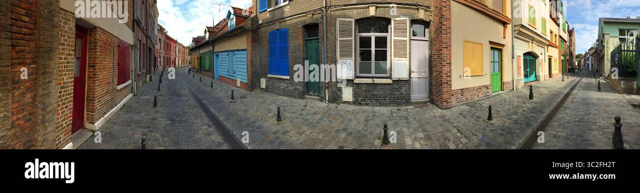 Ein Panoramablick auf eine malerische Stadtstraße mit Kopfsteinpflaster, farbenfrohen Gebäudefassaden und einer Reihe von charmanten architektonischen Elementen. Stockfoto