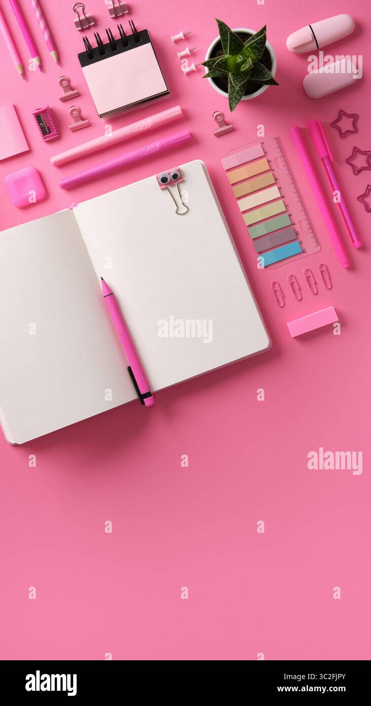 Vertikales Schreibwarenbanner mit offenem Notizbuch mit Schreibwaren in rosa Motiven. Stockfoto