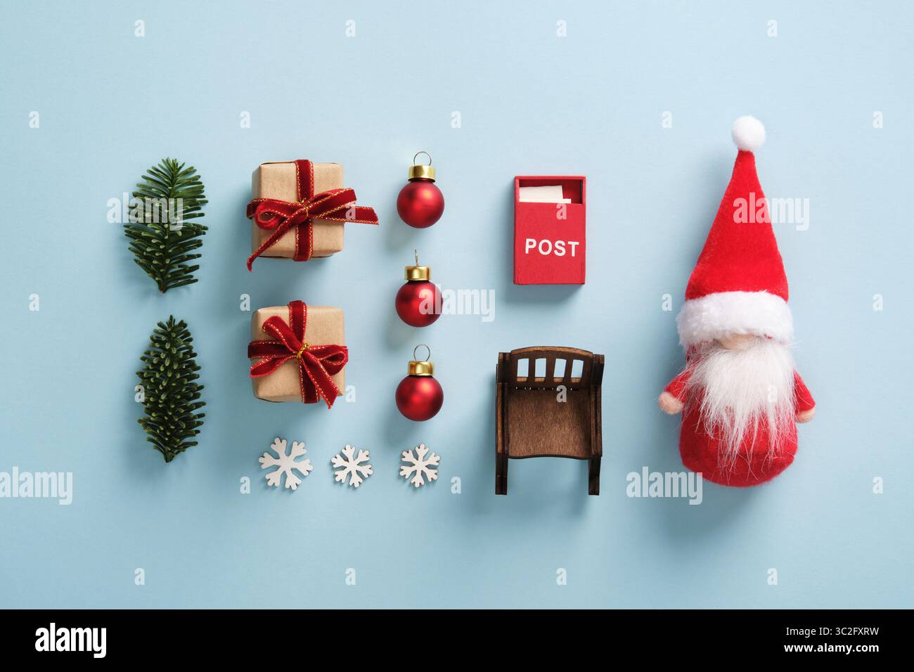 Flache Lage mit Weihnachtsdekoration mit Weihnachtsgeschenken und Miniaturgeschenken, Kugeln, Weihnachtsbaumzweigen, Schneeflocken, Schaukelstuhl und Briefkasten auf hellem blu Stockfoto
