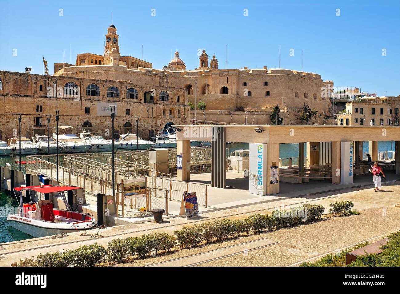 Bormla, Malta - 07.13.2025: Moderner überdachter Fährhafen mit Bänken und Metalltüren für den ein- und Ausstieg der Passagiere an einer sonnigen Uferpromenade mit Dockingstation Stockfoto