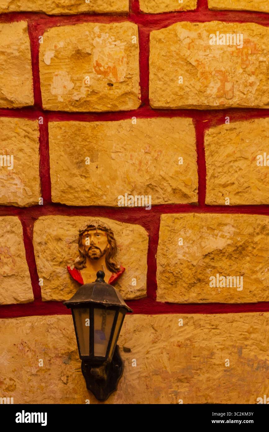 Rustikale Wand mit religiöser Skulptur und Laterne-Beleuchtung Stockfoto