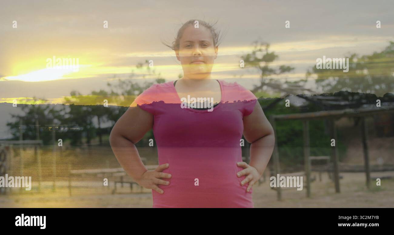 Stehende Frau mit passendem Workout-Top, posiert im Fitness-Park, mit Klimmzugstangen. Fitness, Outdoor, Sonnenuntergang, Wellness, Kraft, Natur, Silhouette Stockfoto