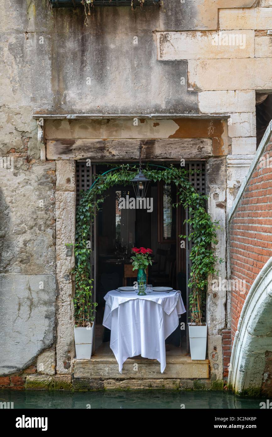 Ruhiger romantischer Tisch am Kanal, Tisch mit Blumen dekoriert, in Venedig Italien Stockfoto