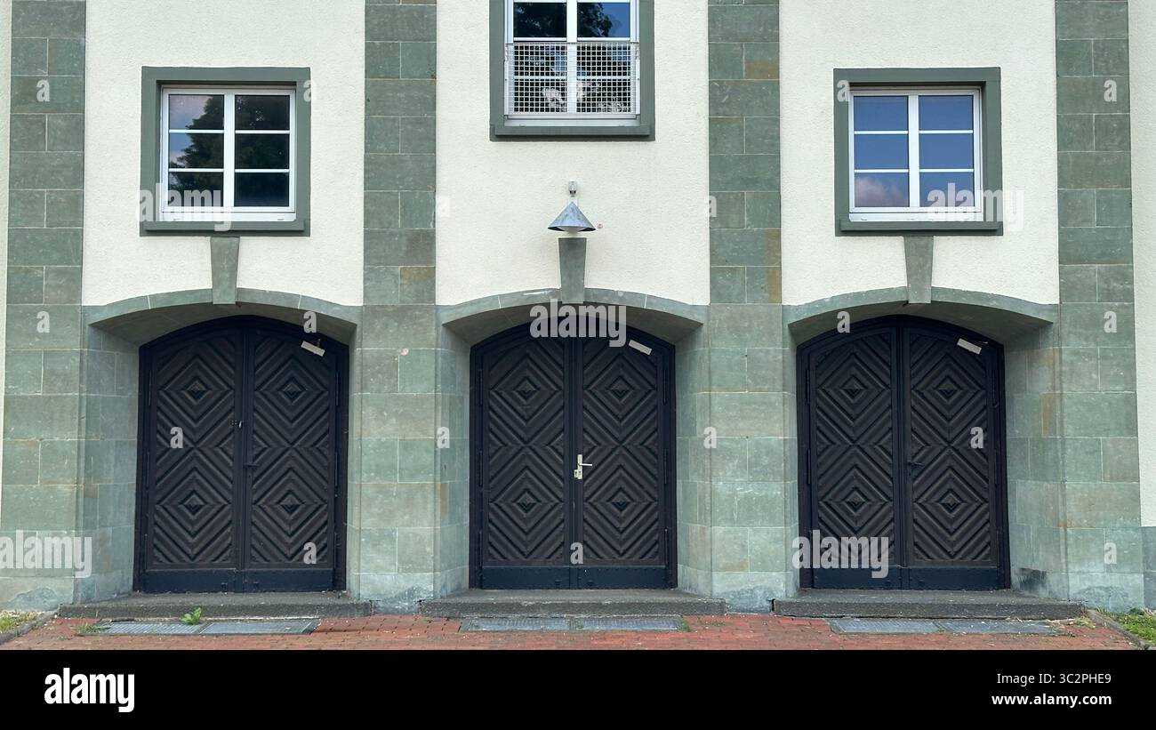 Drei detaillierte Holztüren mit kunstvollen Schnitzereien in bogenförmigen Steinrahmen des ehemaligen Gebäudes der britischen Armee in Herford, Deutschland. Stockfoto