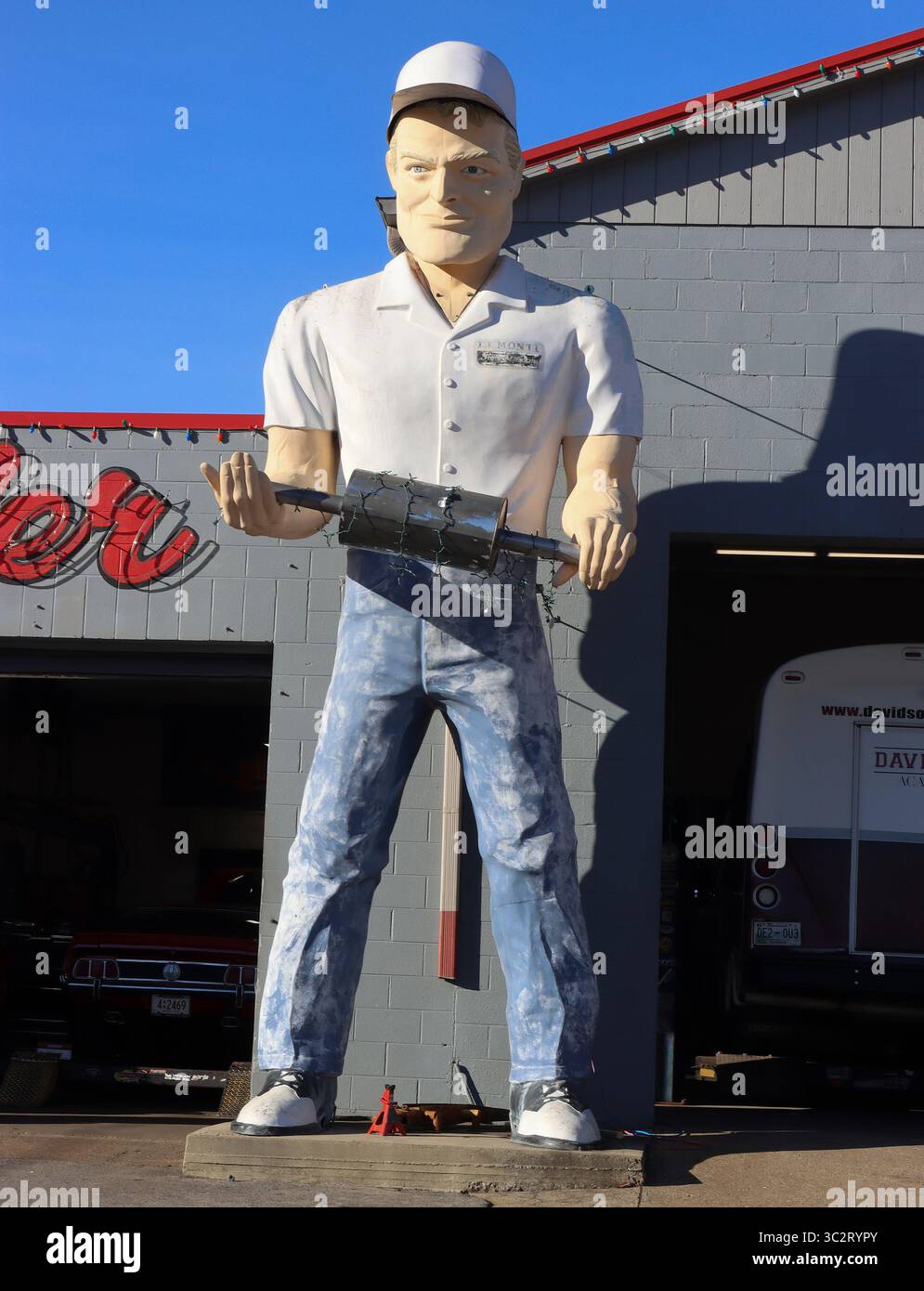 Ein klassischer Schalldämpfer hält einen echten Schalldämpfer in Cookeville, Tennessee, und steht hoch wie eine Straßenfigur mit praxisnahem Reparaturansatz. Stockfoto