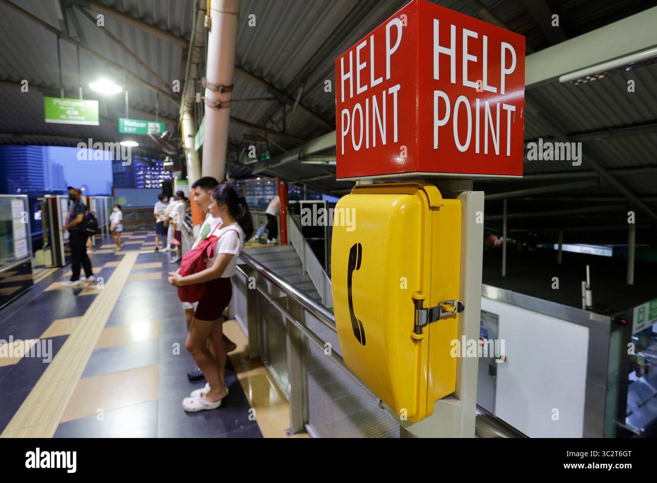 Kuala Lumpur, Malaysia - 27. November 2022: Ein Notruftelefon wird neben Pendlern an einem Bahnsteig einer U-Bahn-Station gesehen. Stockfoto