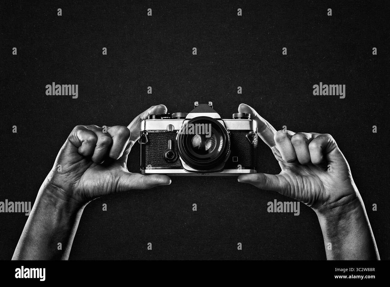 Arme hoch halten Vintage-Kamera in Schwarz-weiß auf schwarzem strukturiertem Hintergrund, Kopierraum Stockfoto Arme hoch halten Vintage-Kamera in Schwarz-weiß auf schwarzem strukturiertem Hintergrund, Kopierraum Stockfoto