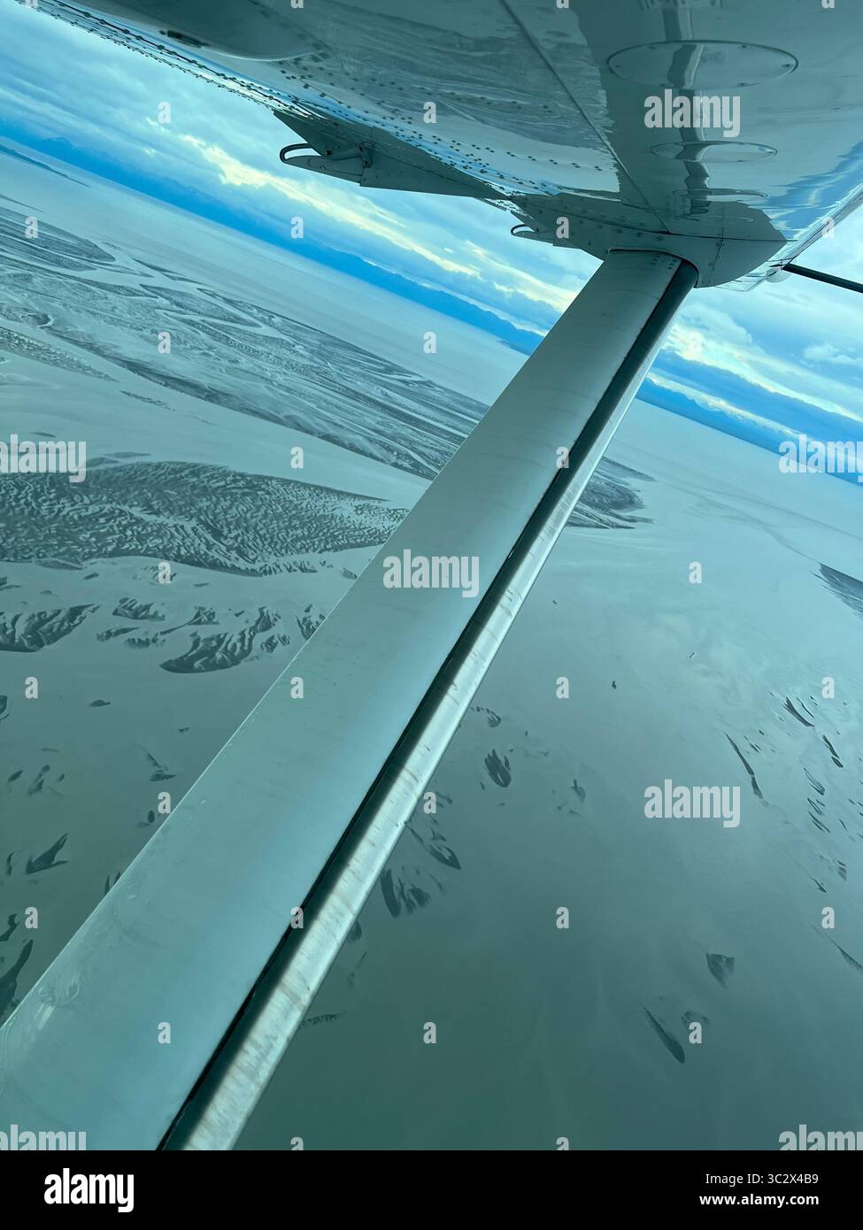 Aus der Vogelperspektive von einer Flugzeugflügelstrebe über die weite Wildnis Alaskas auf dem Weg zum Lake Clark National Park. Abgelegene Flüsse, Feuchtgebiete und unberührtes Land - Smartphone-aufgenommenes Stockfoto