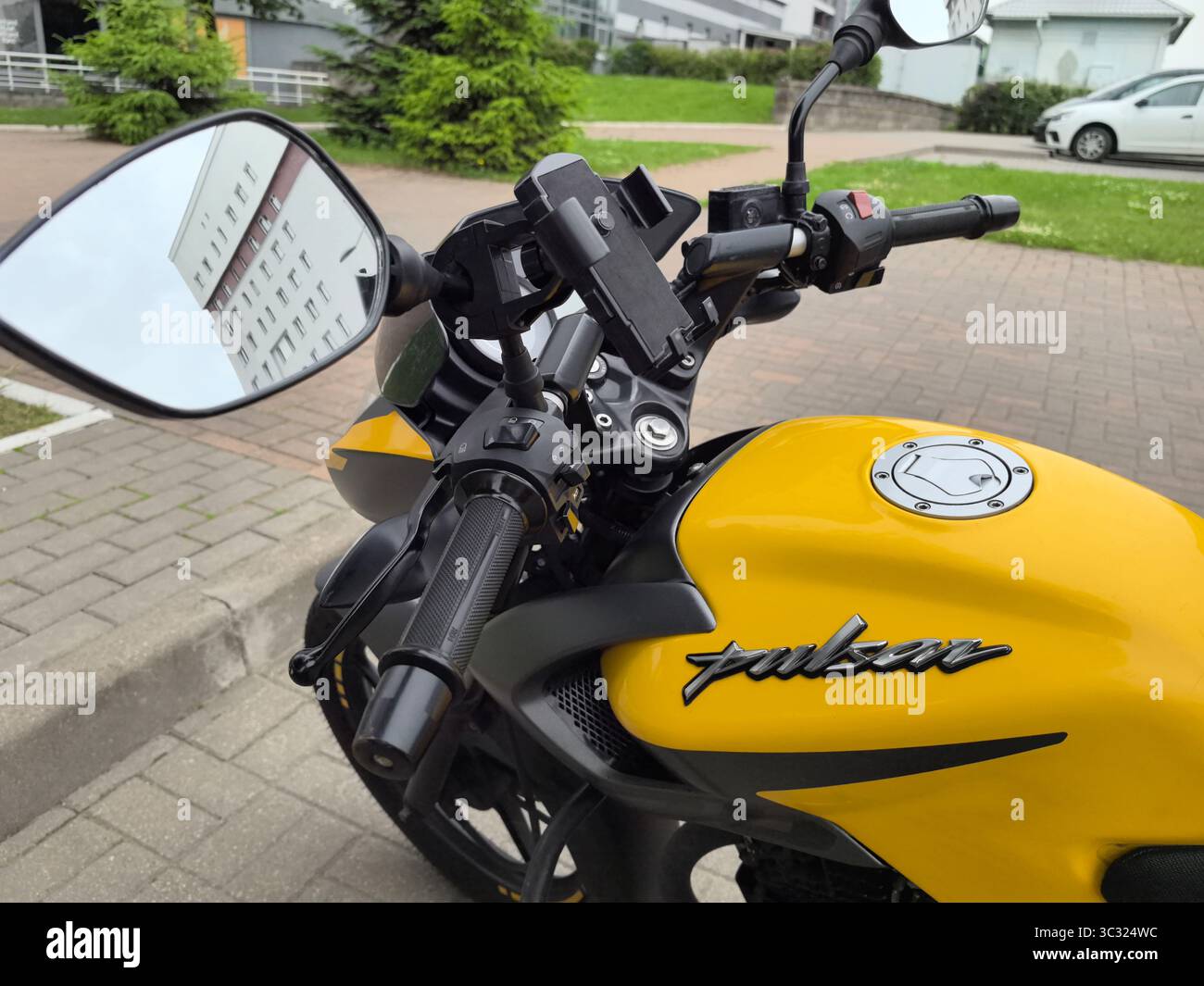 Babruisk, Weißrussland - 18. Juni 2025: Ein leuchtend gelbes Motorrad steht auf einem grünen Gelände in einer ruhigen Nachbarschaft und zeigt sein elegantes Design A Stockfoto