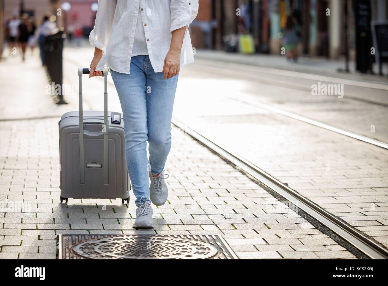 Eine Frau, die den Koffer zieht und auf der Stadtstraße läuft. Alleinreisender Lifestyle Stockfoto