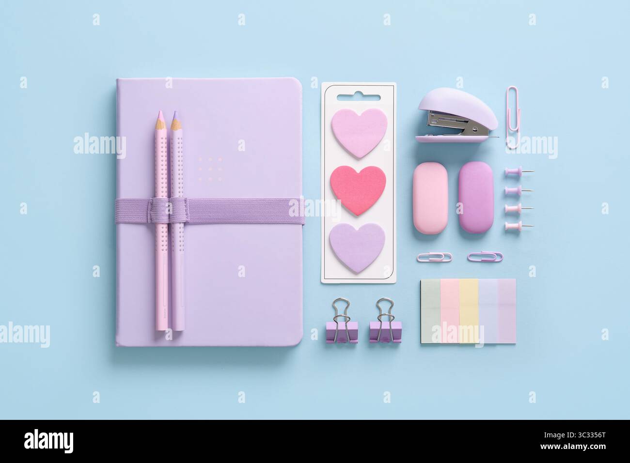 Komposition verschiedener Schul- und Bürounterlagen in pastellrosa und violetten Farben auf blauem Hintergrund. Ein Ort für Ihre SMS. Stockfoto