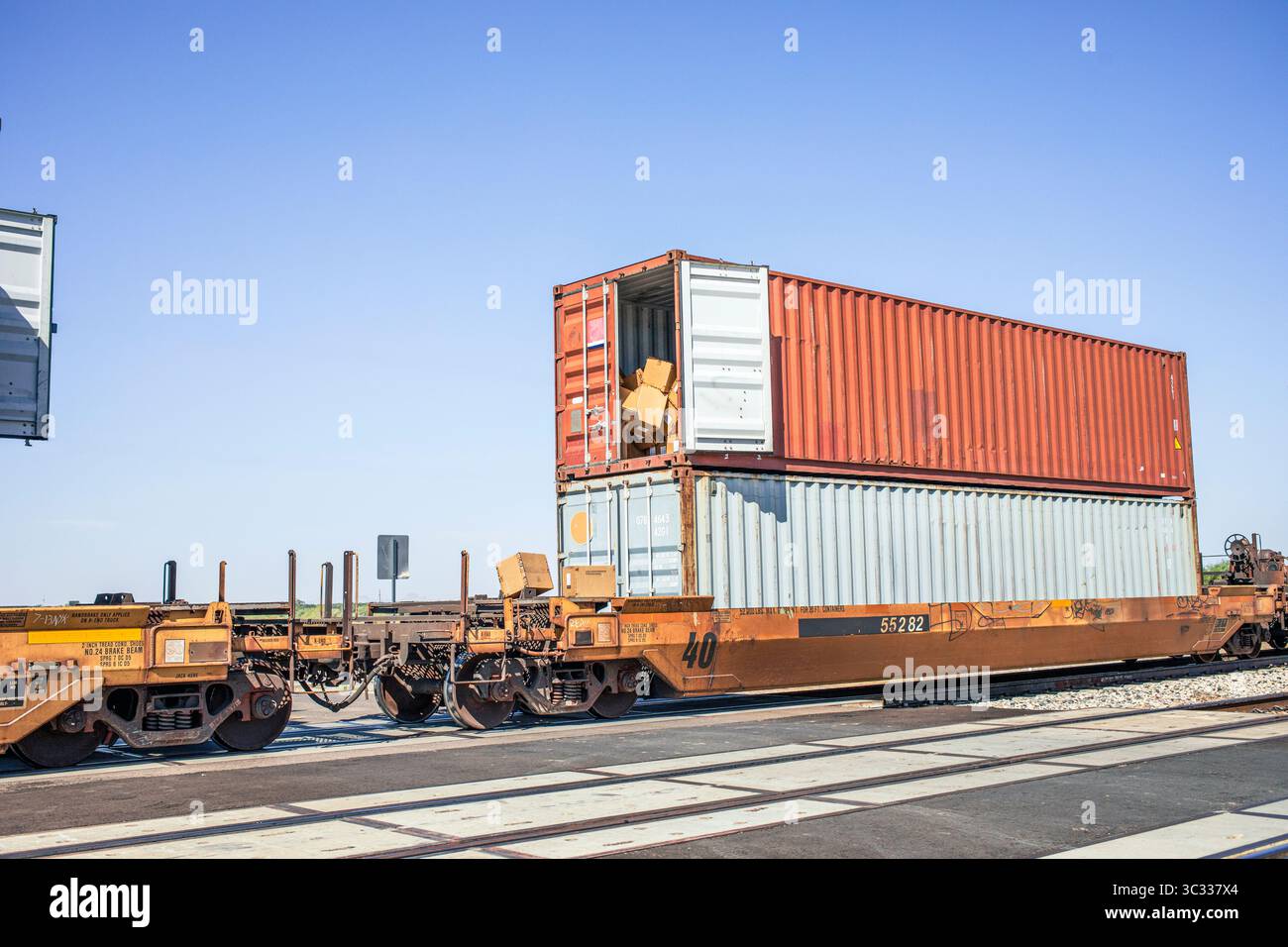 Ein offener Frachtcontainer in einem Zug mit herausfallenden Kisten Stockfoto