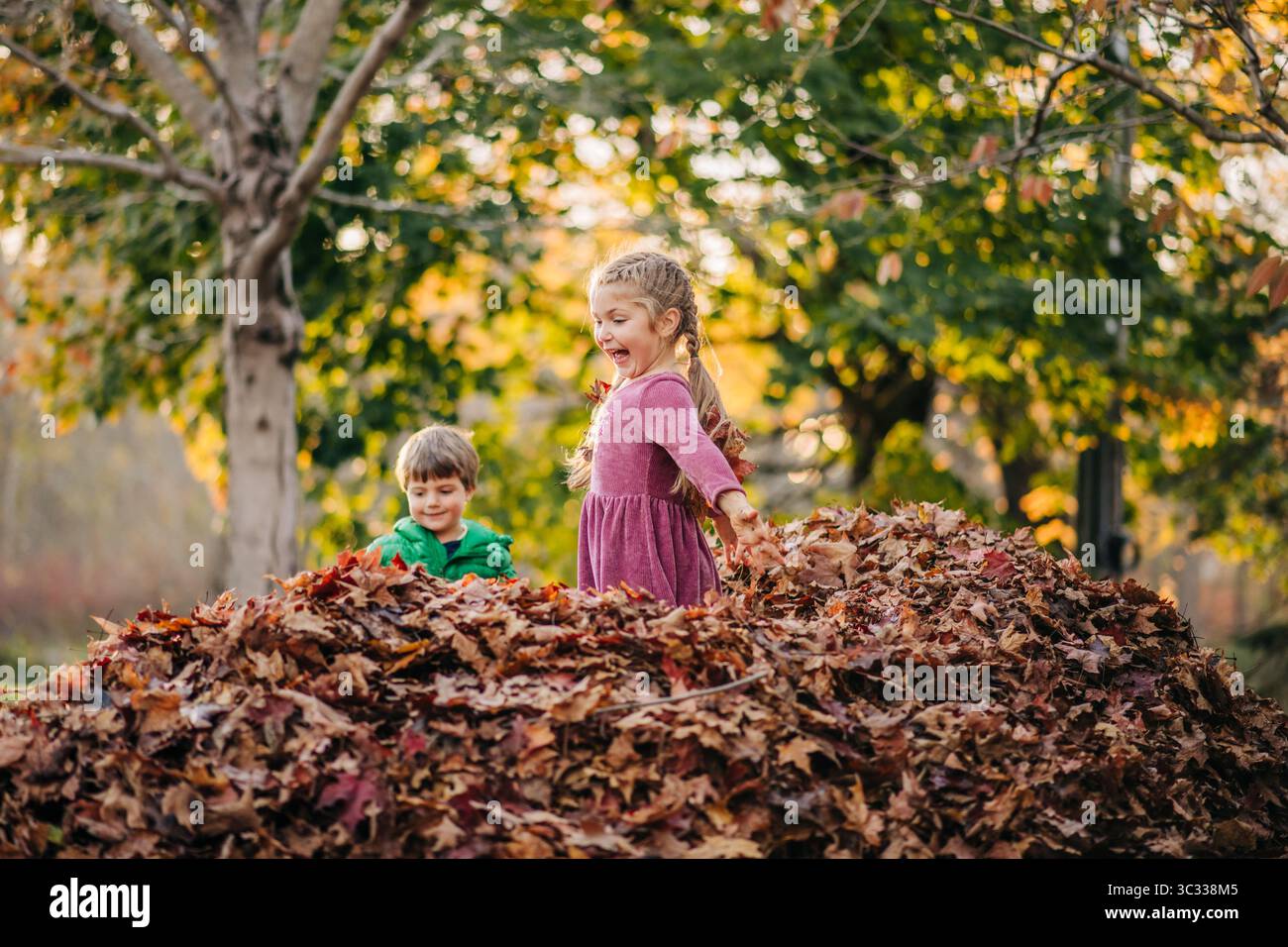 Aufregende Kinder, die in einem Herbstlaub im Park spielen Stockfoto