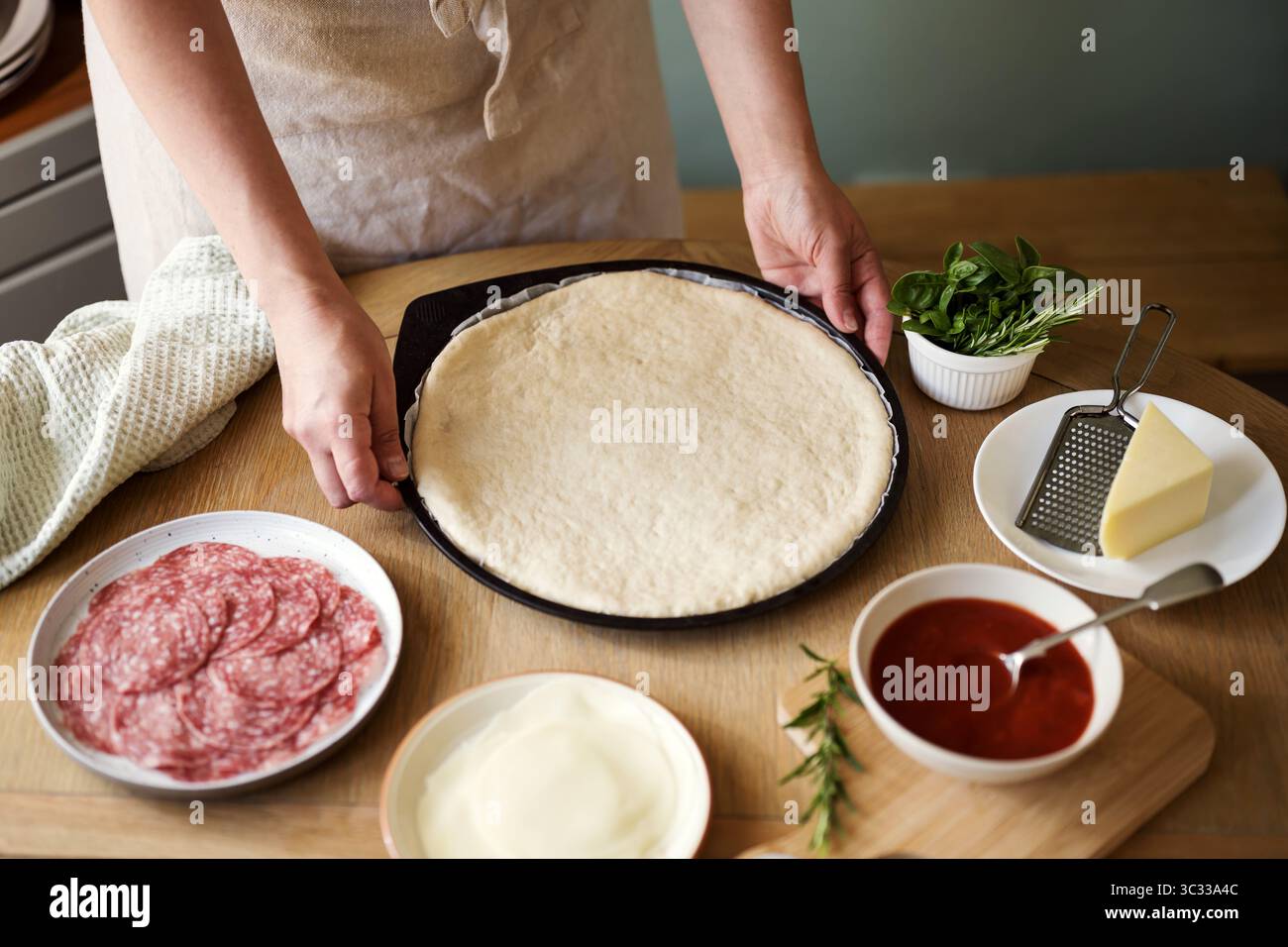 Zutaten zum Kochen von Pizza, weibliche Hände, die Pizzateig halten Stockfoto