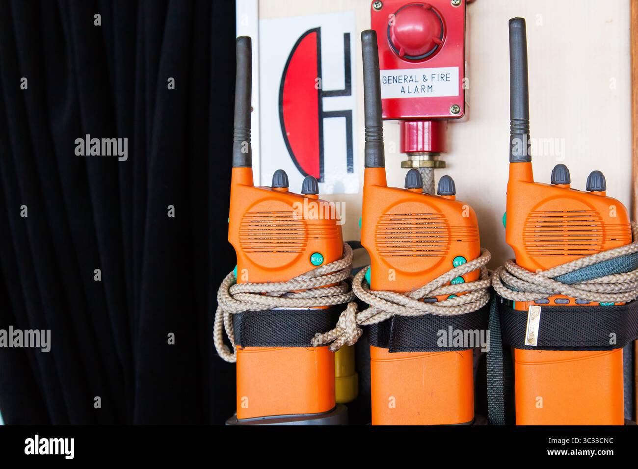 Drei orange Notrufradios auf einem Schiff in der Nähe eines Alarms. Bei einem allgemeinen Alarm oder einem Feueralarm anwenden. Stockfoto