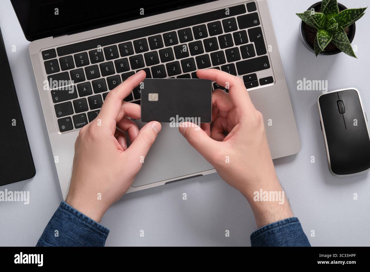 Ein Mann hält eine Bankkarte mit zwei Händen. Online-Zahlungen mit Kreditkarte. Stockfoto