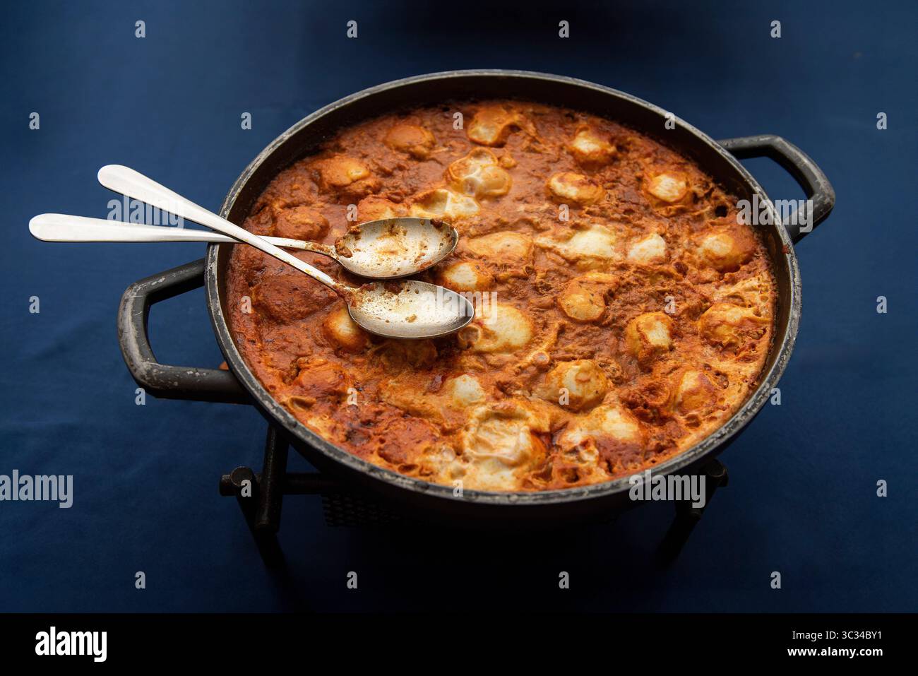 Eine große Pfanne Shakshouka, ein beliebtes maghrebinisches Gericht im Nahen Osten und in Israel, bestehend aus Eiern, pochiert in einer Tomatensoße, Olivenöl und pepp Stockfoto