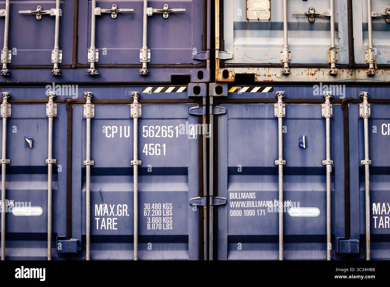 Nahansicht gestapelter Frachtcontainer mit Verriegelungsmechanismen und Markierungen Stockfoto