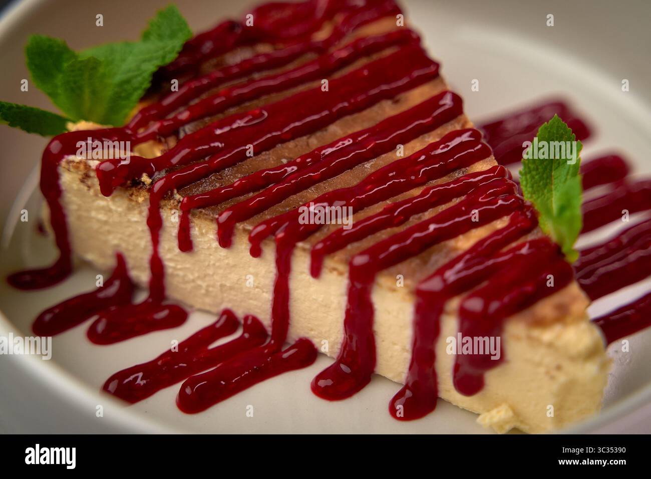 Köstlicher Käsekuchen mit reichhaltiger Beerensauce und frischen Minzblättern, ein perfektes Dessert, um jeden süßen Hunger zu stillen und Ihr Essen zu verbessern Stockfoto