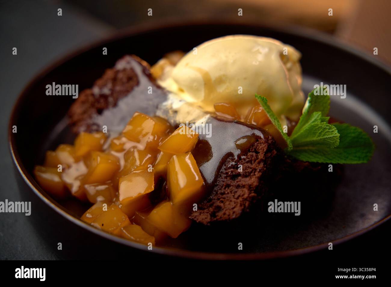 Köstlicher Chocolate Brownie mit cremigem Eis und süßem Obst-Topping für verwöhnte Dessertliebhaber Stockfoto