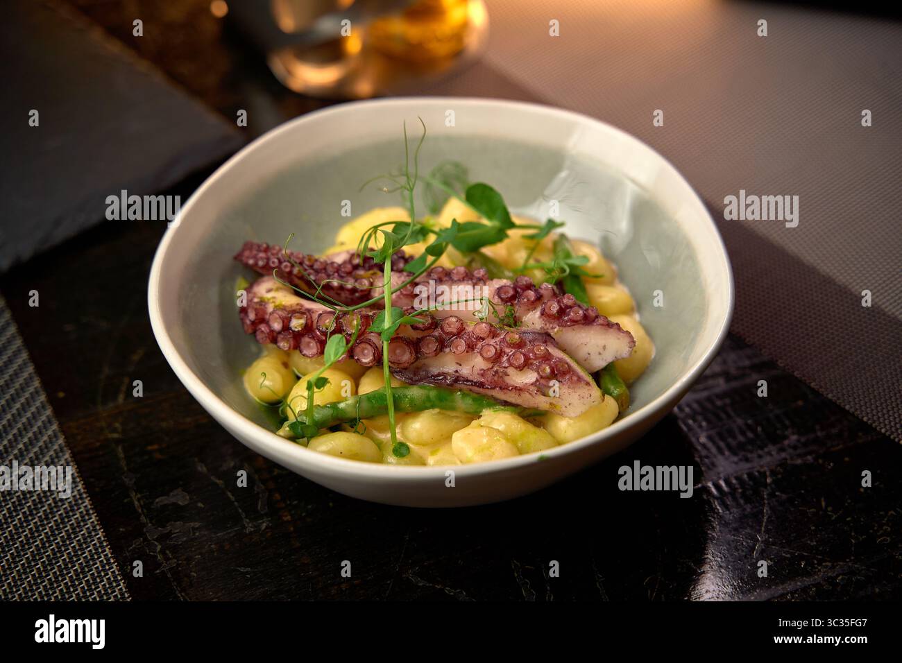 Ein wunderschön arrangiertes Gericht mit zartem Oktopus und cremigem Gnocchi mit frischem Grün, das eine perfekte Balance aus Aromen und Texturen bietet Stockfoto