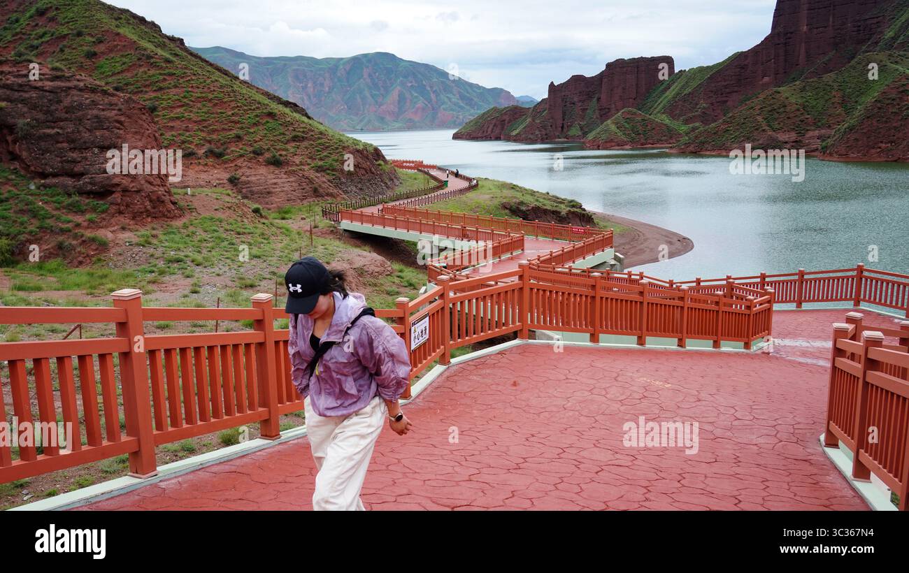 (250725) -- JAINCA, 25. Juli 2025 (Xinhua) -- Ein Tourist besucht den Kanbula National Geopark in der tibetischen Autonomen Präfektur Huangnan, nordwestchinesische Provinz Qinghai, 24. Juli 2025. Der Kanbula National Geopark liegt am nordöstlichen Rand des Qinghai-Tibet-Plateaus und erstreckt sich über etwa 3.149 Quadratkilometer mit markanten, feurroten Danxia-Landschaften, hoch aufragenden zerklüfteten Gipfeln, versteckten Höhlen und smaragdgrünen Seen. Abgesehen von seiner visuellen Pracht liegt der wahre Wert des Parks unter der Oberfläche und ist ein erstklassiger Standort für geowissenschaftliche Forschung und Public Science Education. (Xinhua/Qi Zhiyue) Stockfoto
