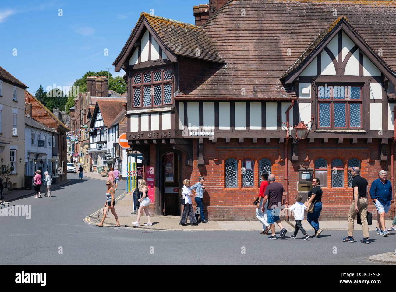 Postamt im Stil von Mock Tudor, an dem im Sommer Leute vorbeilaufen, am Postgebäude in der Marktstadt Arundel, West Sussex, Großbritannien. Stockfoto