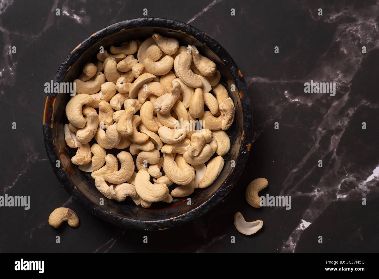 Eine rustikale Schüssel gefüllt mit rohen Cashewnüssen, die ihr natürliches Aussehen hervorheben und die gesundheitlichen Vorteile fördern, die mit diesen leckeren und Nüssen verbunden sind Stockfoto