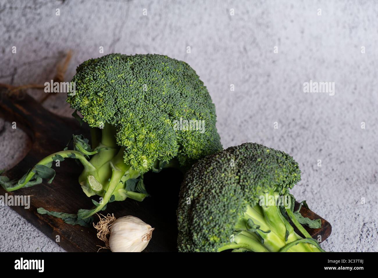 Eine lebendige Präsentation frisch geernteter Brokkoli-Röschen auf einem rustikalen Schneidebrett, inspiriert für kreative Kochideen oder gesunde Speisen Stockfoto