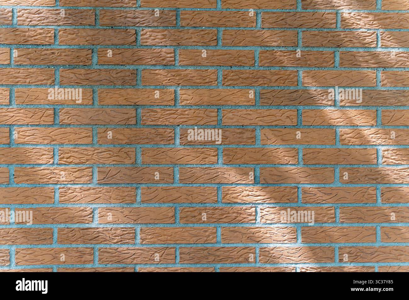 Gemauerte Mauer mit einheitlicher Struktur und Schatten. Nahaufnahme einer rötlichen Ziegelwand mit einheitlicher Gelenkstruktur. Helle Schatten sorgen für Tiefe und Variation Stockfoto