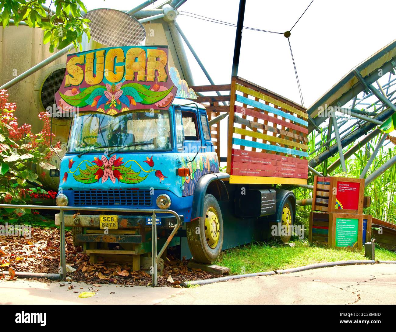 Mehrfarbiger Lkw mit einem großen Zuckerschild, das die Bedeutung des Zuckerrohr-Regenwaldbioms Eden Project Bodelva Cornwall England unterstreicht Stockfoto