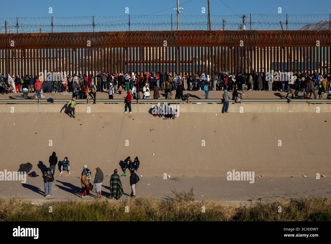 Die Menschen überwinden die Barrieren an der Grenze zu Ciudad Juarez und heben die Herausforderungen der Migration hervor. Stockfoto