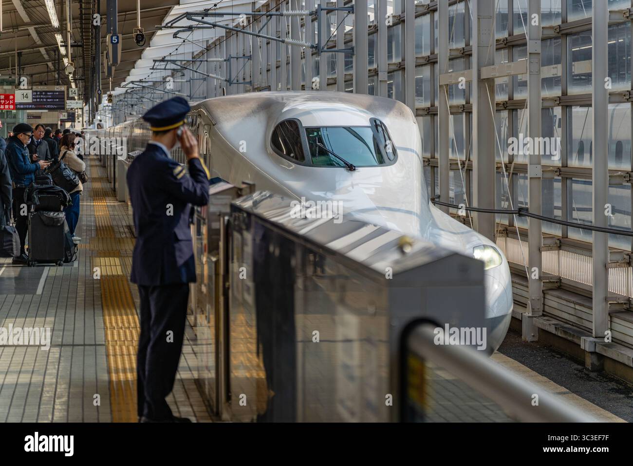 Tokio, Japan - 15. Januar 2025 Eisenbahnarbeiter in Uniform begrüßt den Shinkansen-Hochgeschwindigkeitszug im Bahnhof. Stockfoto