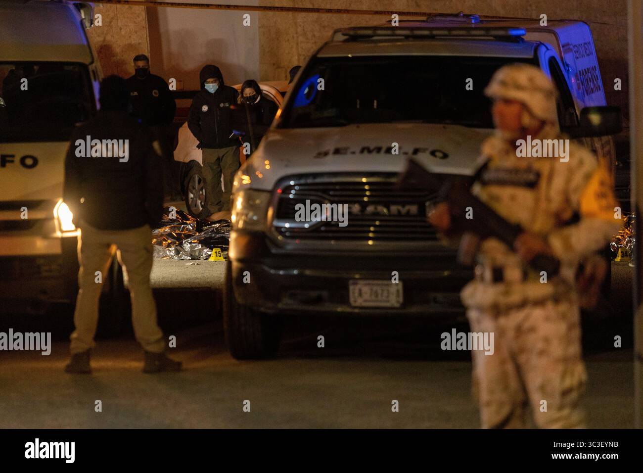 Forensische Beamte untersuchen einen nächtlichen Tatort in der Nähe von Ciudad Juarez, einem Hotspot für Grenzstreitigkeiten und Migrationsprobleme, unter strenger Sicherheit. Stockfoto