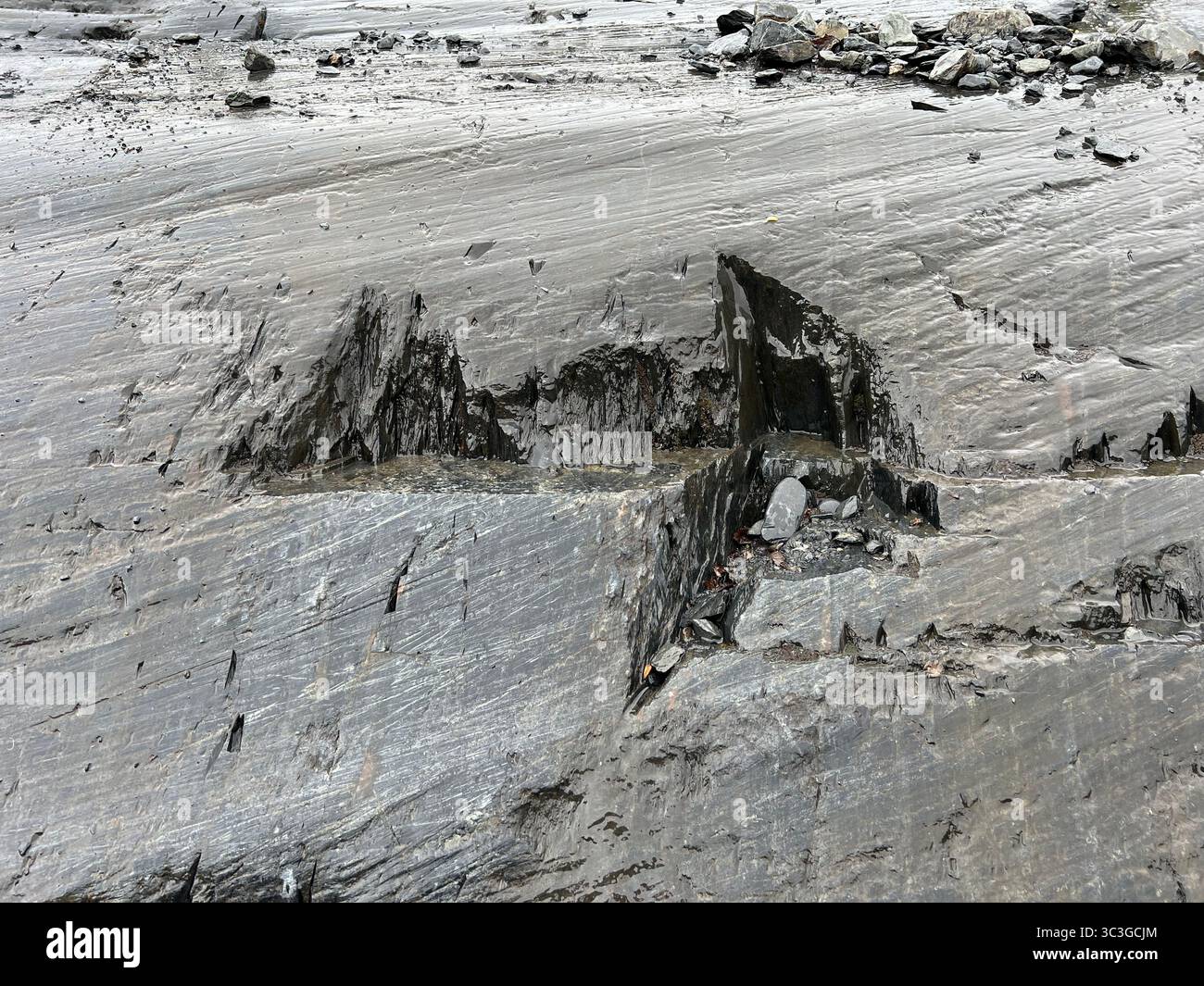 Nahaufnahme des Gletscherfelsens im Glacier Bay National Park, Alaska – strukturierte geologische Oberfläche, die durch antike Erosion und Gletscherbewegungen geformt wurde. - Smartphone-aufgenommenes Stockfoto