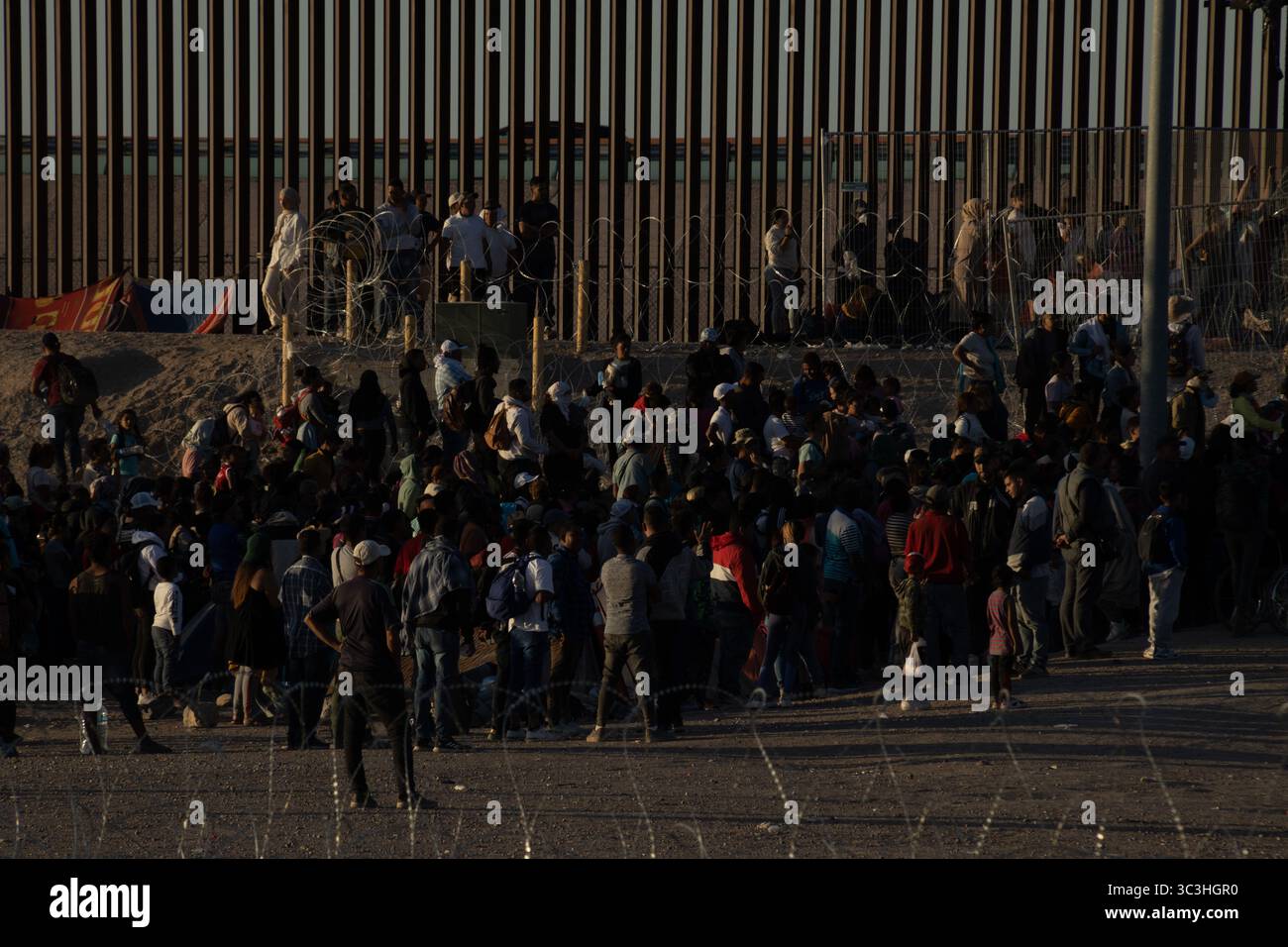 Gruppe am Grenzzaun von Ciudad Juarez, die Migrationsherausforderungen veranschaulicht. Stockfoto