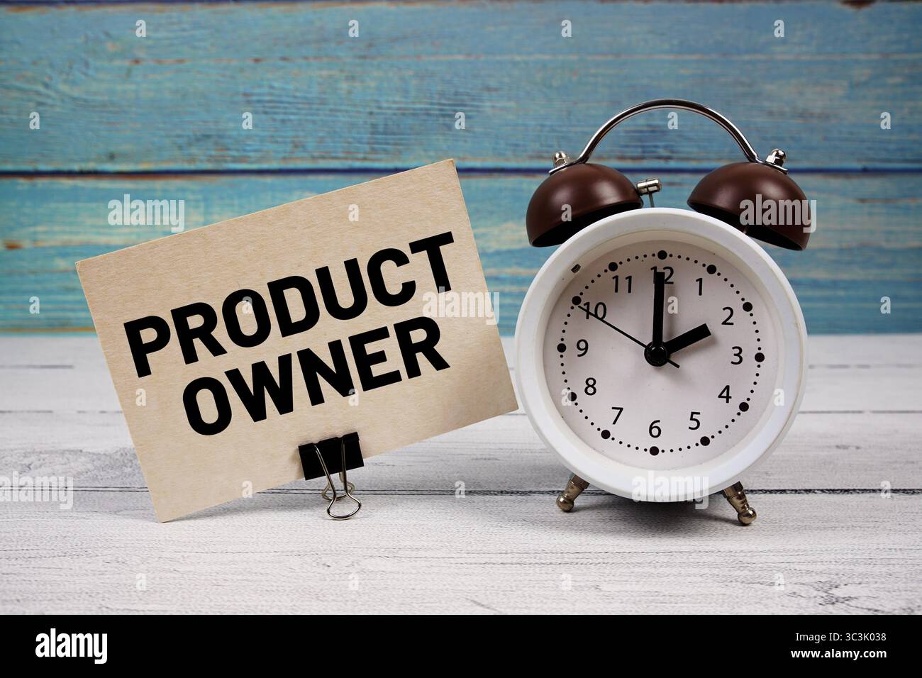 Text des Produkteigentümers auf Papierkarte mit Wecker auf hölzernem Hintergrund geschrieben Stockfoto