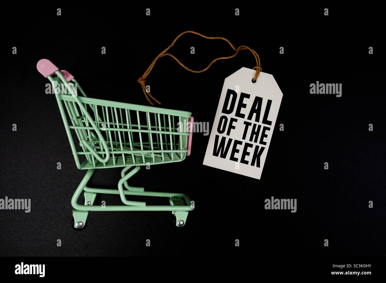 Text zum Angebot der Woche auf Preisschild und Einkaufswagen auf schwarzem Hintergrund Stockfoto