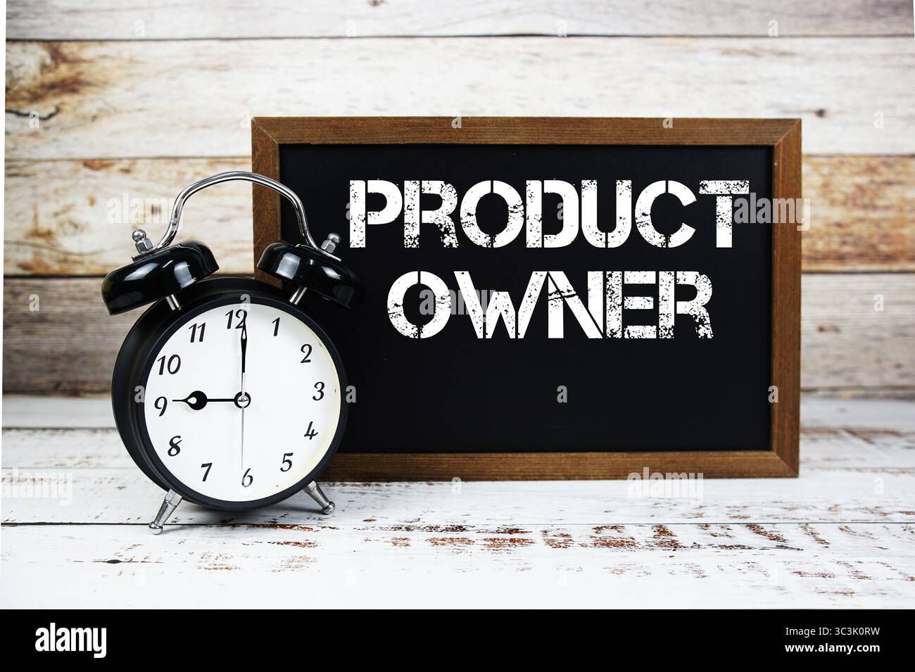Textnachricht und Wecker des Produkteigentümers auf hölzernem Hintergrund Stockfoto