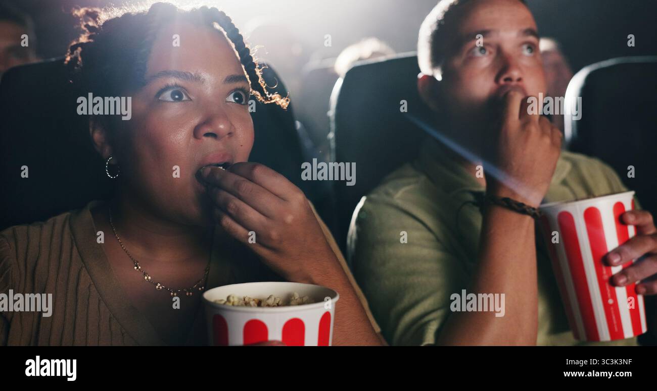 Paare, Popcorn und Horrorfilm im Theater mit Snack, Date und Unterhaltung bei Filmvorführung. Leute, Mann und Frau mit Schock für Thriller in Stockfoto